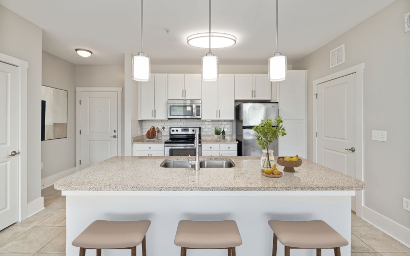 A modern kitchen featuring sleek white cabinetry with brushed nickel hardware, complemented by granite countertops.