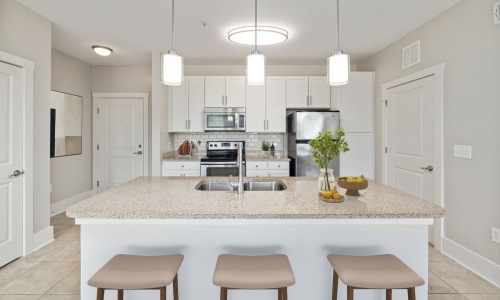 Upscale Apartment Interiors A modern kitchen featuring sleek white cabinetry with brushed nickel hardware, complemented by granite countertops.